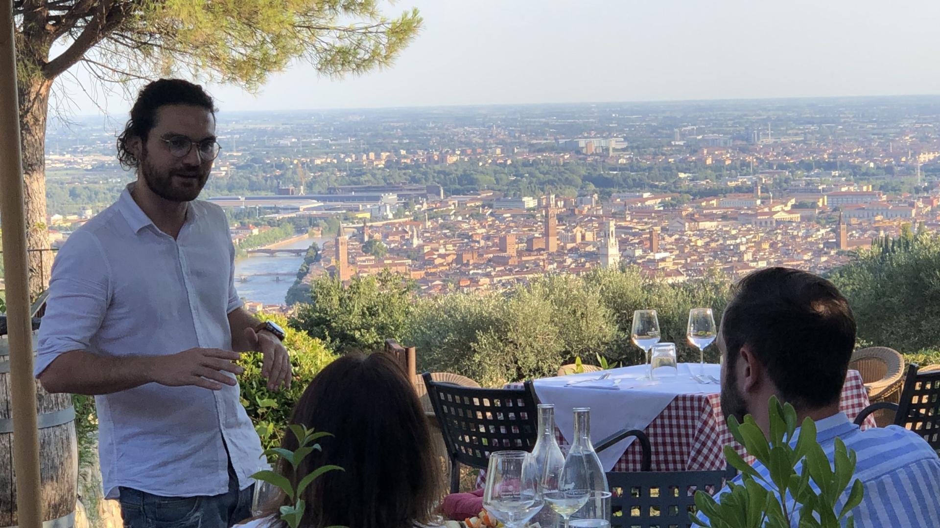 Due mani brindano con bicchieri di vino rosso e bianco all'aperto.