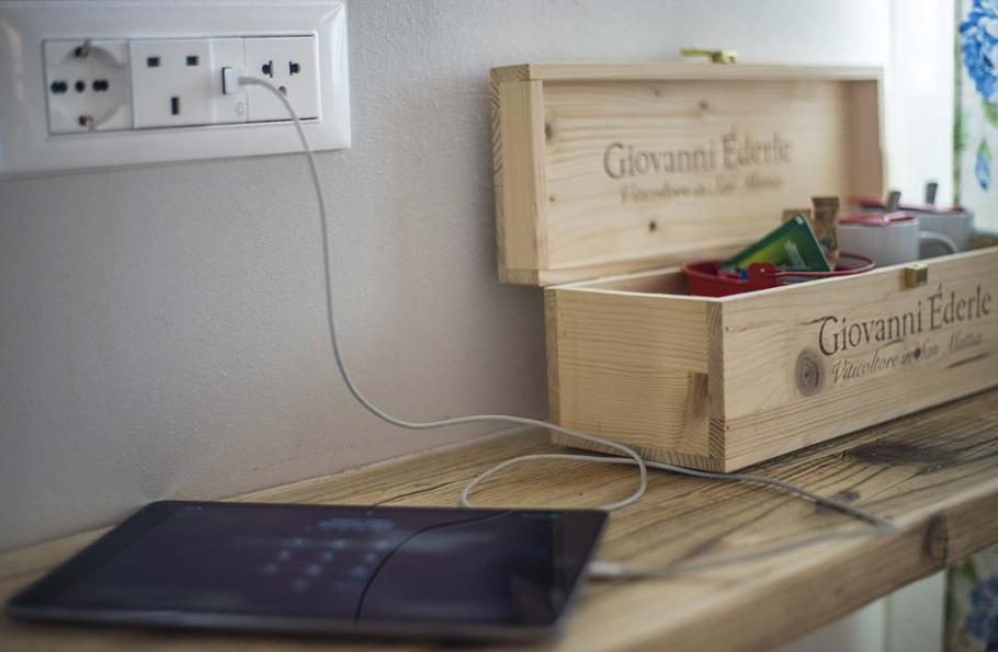 Tablet in carica su un tavolo di legno accanto a una scatola di legno aperta.