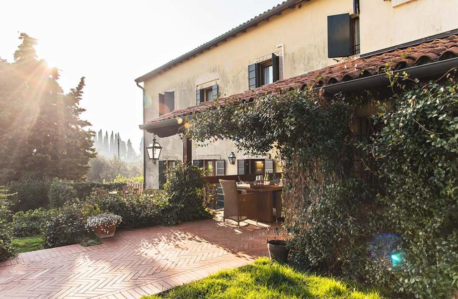 Casa rustica con giardino, terrazza e luce solare filtrata tra gli alberi.