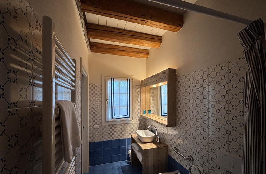 Bagno con piastrelle blu, soffitto con travi in legno e lavabo moderno.