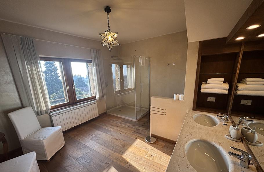 Bagno elegante con doppio lavabo, doccia in vetro e vista panoramica.