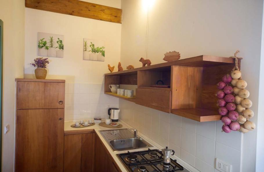 Cucina rustica con mobili in legno, decorazioni e trecce di aglio e cipolle.