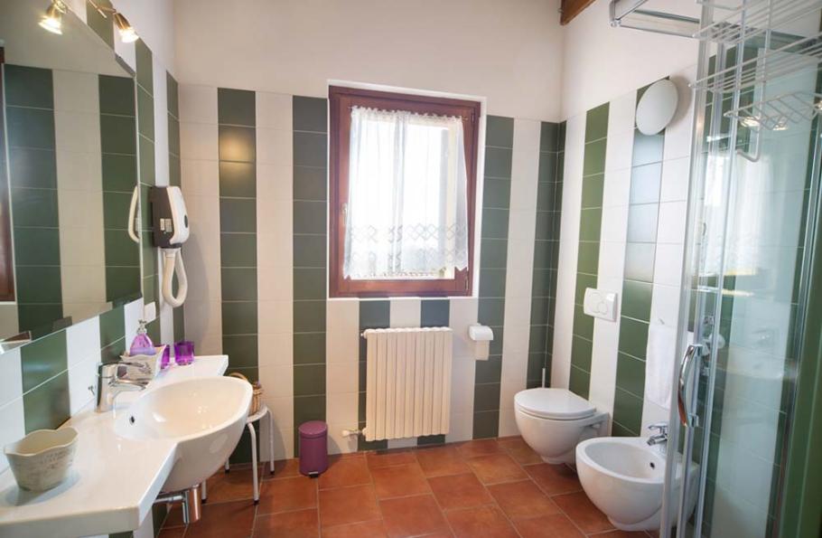 Bagno moderno con piastrelle verdi e bianche, lavabo, bidet, WC e doccia.