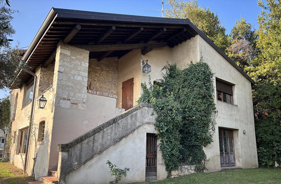 Casa rustica con pietra a vista, scala esterna e rampicante sulla facciata.